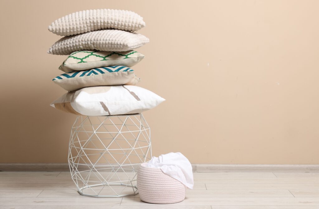 Stack of soft pillows on small table indoors. Space for text